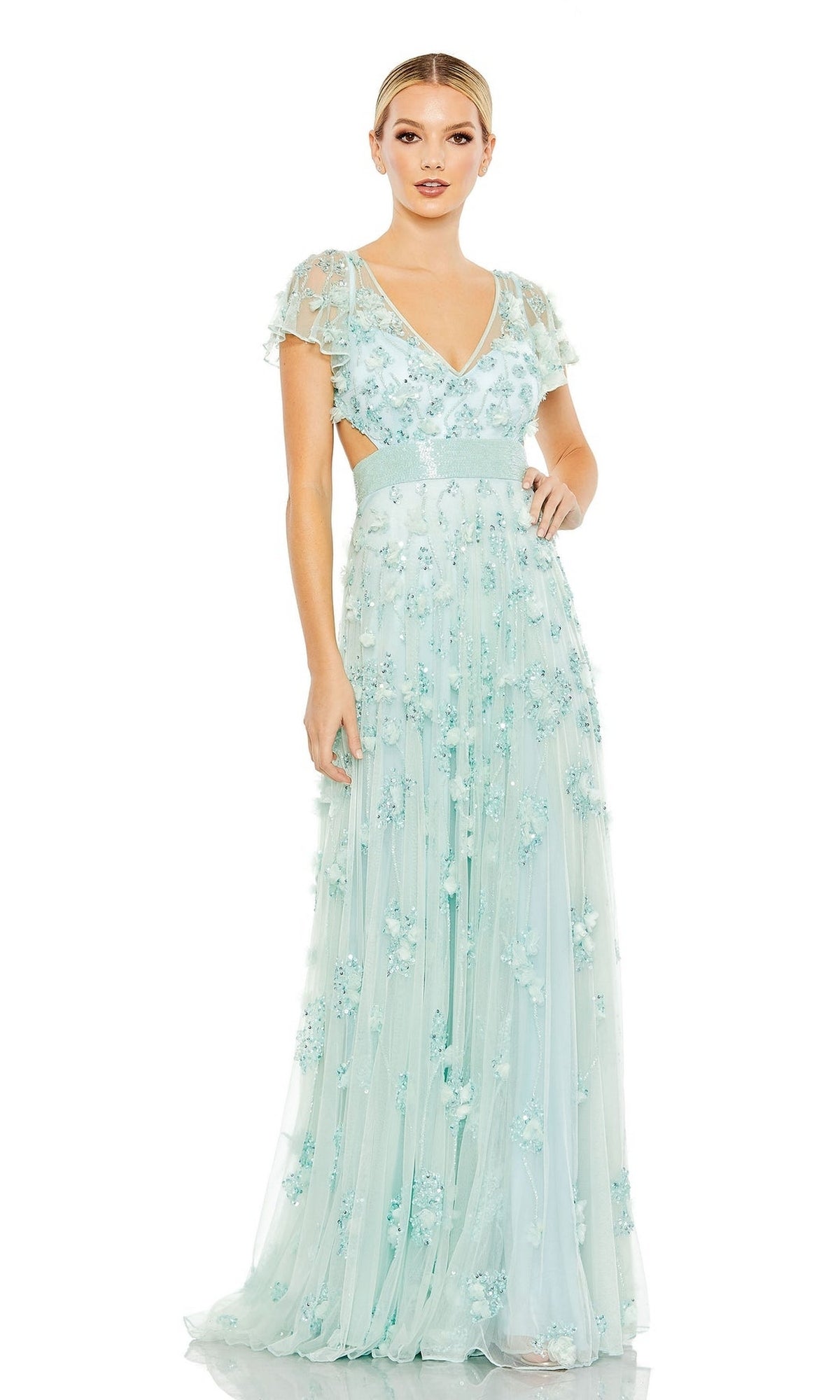 A woman stands against a white background wearing the Long Formal Dress 70275 by Mac Duggal, a light blue, floor-length A-line gown with short sleeves, embellishments, and floral appliqué details.